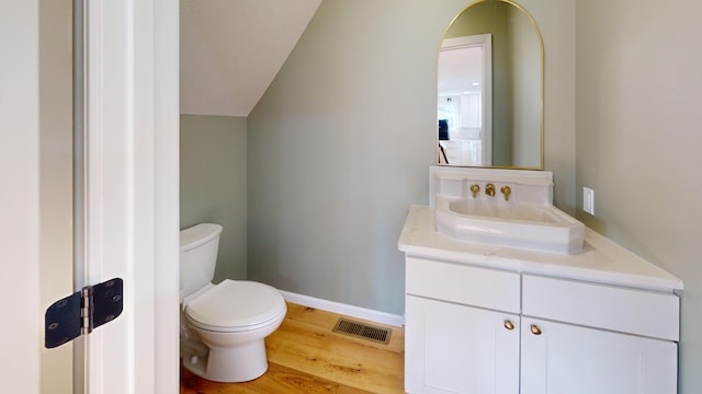 bathroom with hardwood / wood-style floors, vanity, toilet, and vaulted ceiling