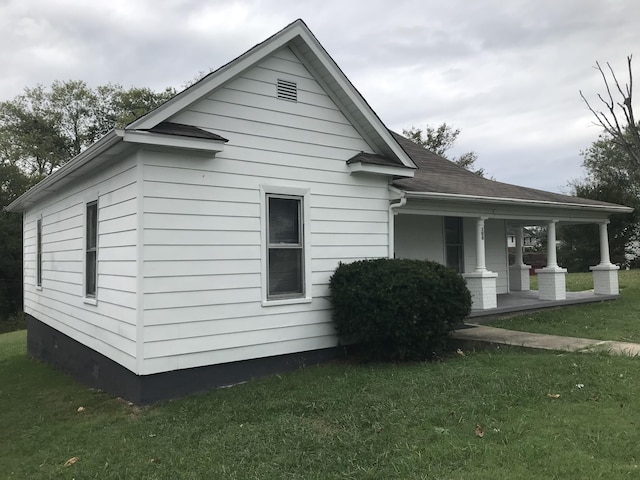 view of side of property featuring a lawn and covered porch