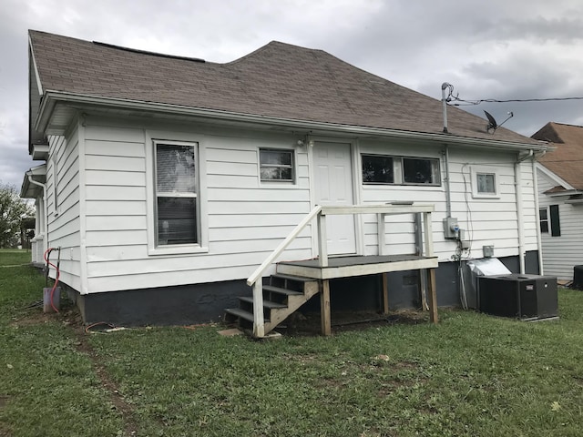 back of house featuring central air condition unit and a lawn