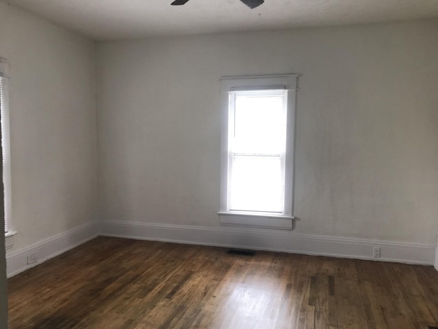 unfurnished room featuring a wealth of natural light, dark hardwood / wood-style flooring, and ceiling fan