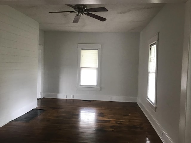 unfurnished room with ceiling fan, dark hardwood / wood-style floors, and a wealth of natural light