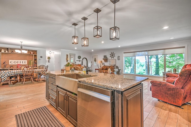 kitchen featuring a sink, open floor plan, stainless steel dishwasher, and light wood-style floors
