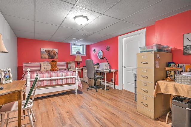 bedroom featuring a drop ceiling, baseboards, and wood finished floors