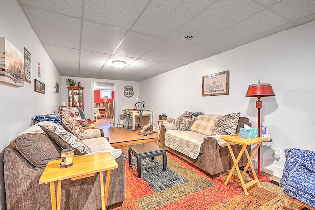 living room featuring a paneled ceiling, wood finished floors, and visible vents