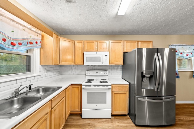 kitchen featuring light brown cabinetry, sink, tasteful backsplash, light wood-type flooring, and white appliances