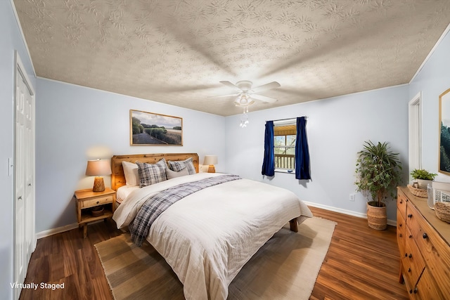 bedroom with ceiling fan, dark hardwood / wood-style floors, and a textured ceiling