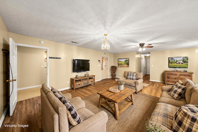 living room featuring wood-type flooring, ceiling fan, and a textured ceiling