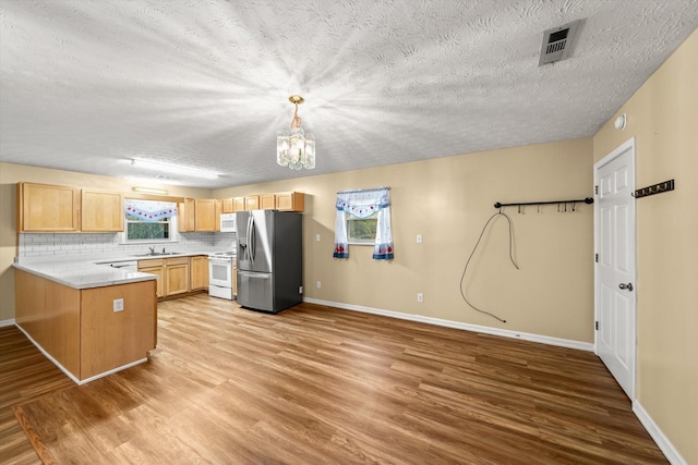 kitchen featuring sink, light brown cabinets, stainless steel fridge, pendant lighting, and white range with electric cooktop