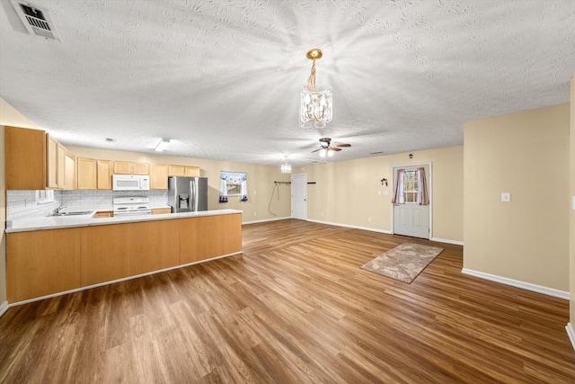 kitchen featuring ceiling fan with notable chandelier, backsplash, white appliances, kitchen peninsula, and light wood-type flooring