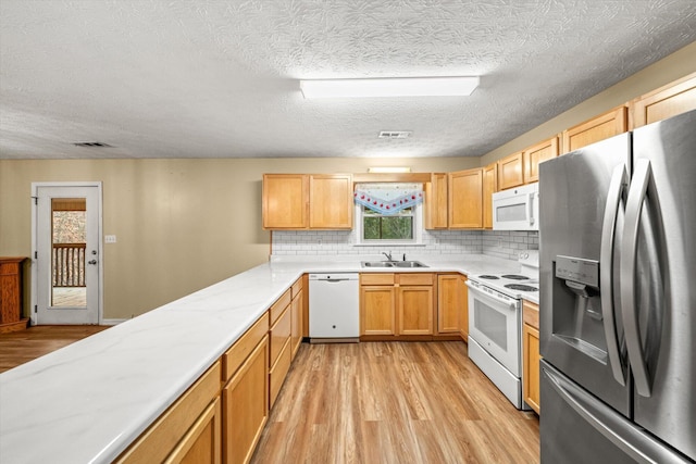 kitchen with sink, white appliances, backsplash, light hardwood / wood-style floors, and a textured ceiling