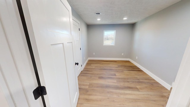 unfurnished room featuring light wood-style flooring, baseboards, a textured ceiling, and recessed lighting