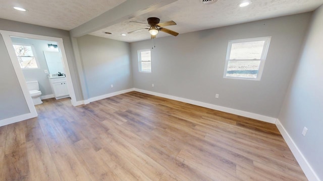 unfurnished bedroom with light wood-type flooring, a textured ceiling, baseboards, and recessed lighting