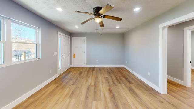 unfurnished room with light wood-style floors, baseboards, a textured ceiling, and recessed lighting