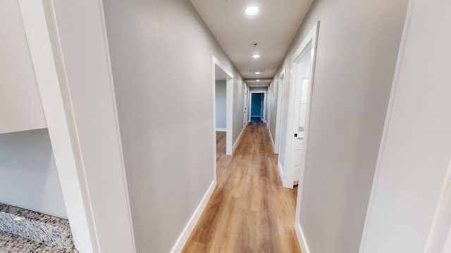 corridor featuring light wood finished floors, recessed lighting, and baseboards