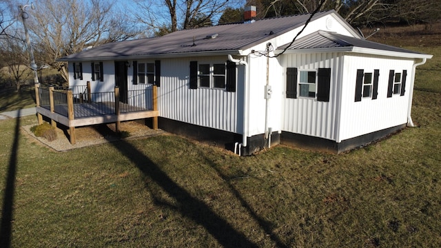 back of property with metal roof, a lawn, and a wooden deck