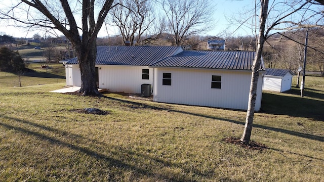 back of house with a garage, metal roof, and a lawn