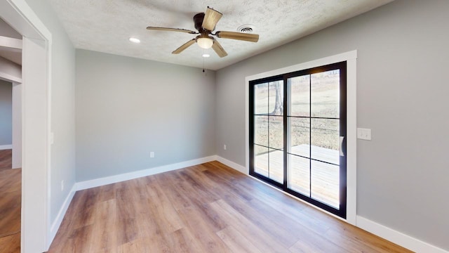 empty room featuring ceiling fan, a textured ceiling, baseboards, and wood finished floors