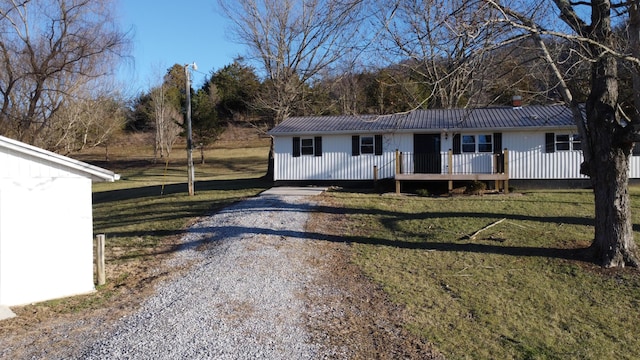 view of front of home with a front yard, gravel driveway, and metal roof