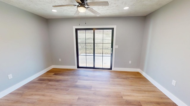 unfurnished room with a textured ceiling, light wood finished floors, and baseboards