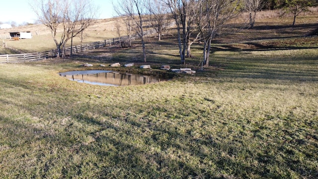 view of yard featuring a rural view, a water view, and fence