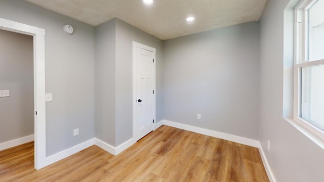 spare room featuring light wood-style floors, recessed lighting, and baseboards