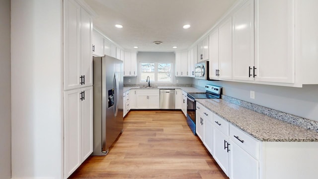 kitchen with light wood-style flooring, stainless steel appliances, white cabinetry, a sink, and recessed lighting