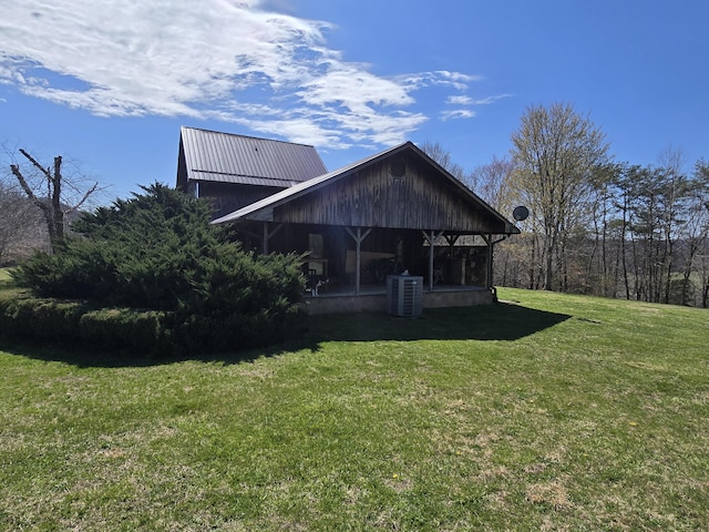 rear view of house featuring central AC and a lawn