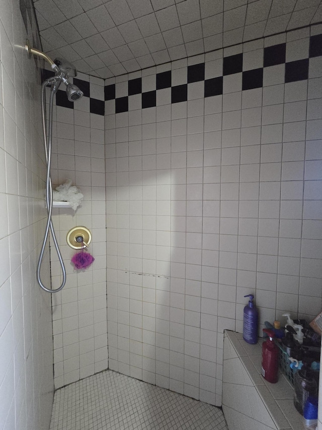 full bath featuring tiled shower and tile walls