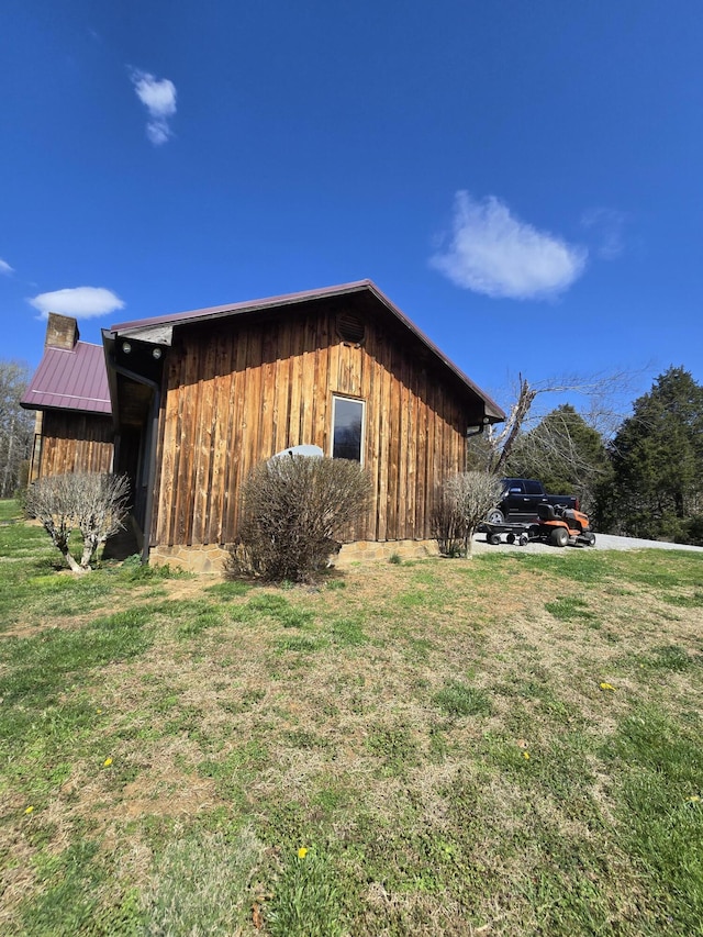 view of side of property with metal roof, a lawn, and a chimney