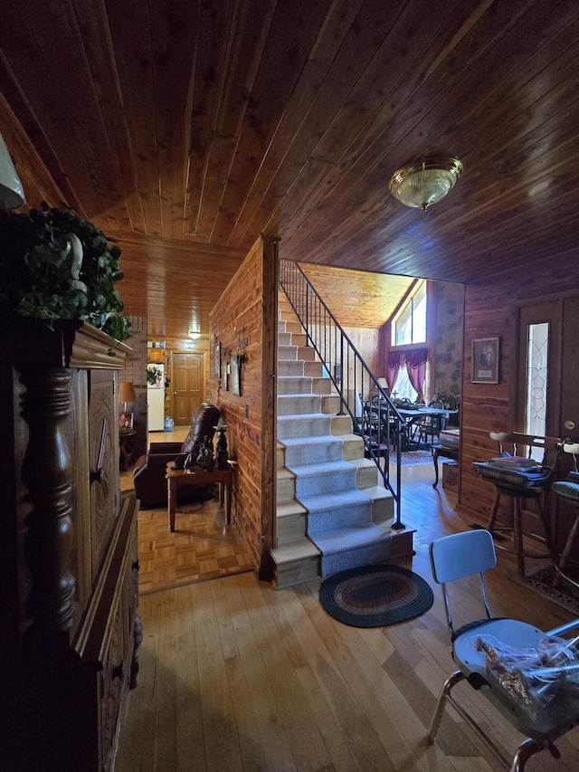 stairs featuring wooden walls, wood ceiling, and wood-type flooring
