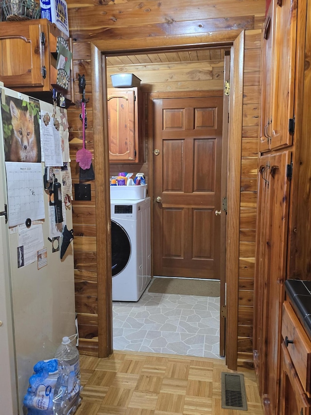 clothes washing area with cabinet space, washer / clothes dryer, and visible vents