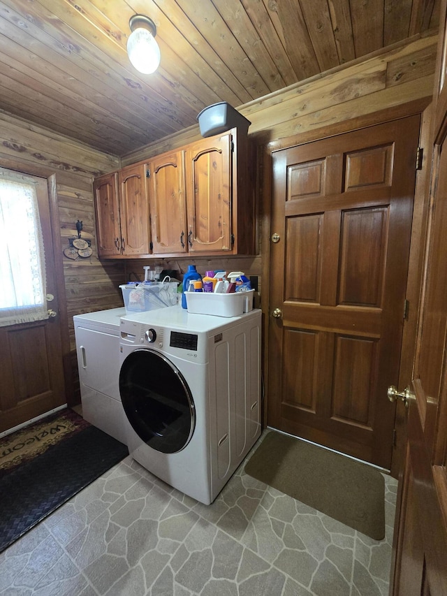washroom with wooden ceiling, wooden walls, stone floors, cabinet space, and washing machine and dryer
