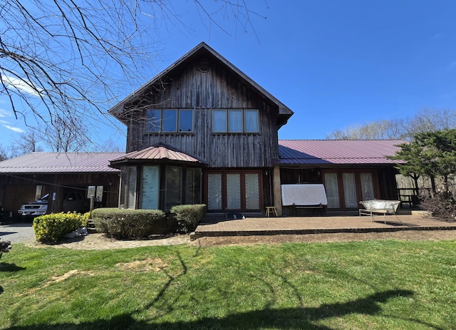 back of house featuring a lawn, metal roof, and a standing seam roof