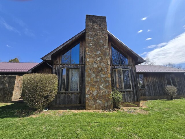 view of side of home with a yard, metal roof, and a chimney