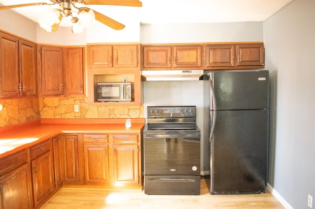 kitchen with freestanding refrigerator, range with electric cooktop, light countertops, under cabinet range hood, and stainless steel microwave