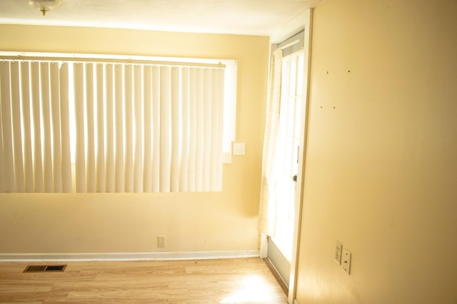 empty room featuring visible vents, baseboards, and wood finished floors