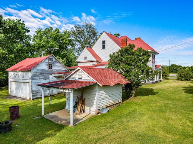 rear view of property featuring a lawn and an outbuilding