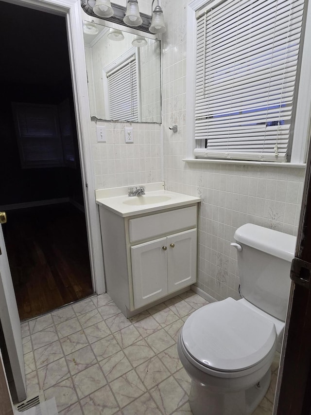 bathroom with vanity, tile walls, and toilet