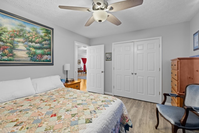 bedroom with a textured ceiling, a closet, ceiling fan, and light hardwood / wood-style floors