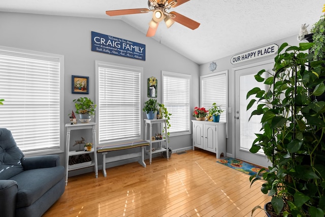 living area featuring a textured ceiling, vaulted ceiling, ceiling fan, and light hardwood / wood-style flooring