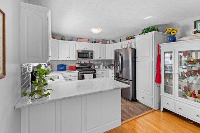 kitchen with appliances with stainless steel finishes, white cabinetry, and kitchen peninsula