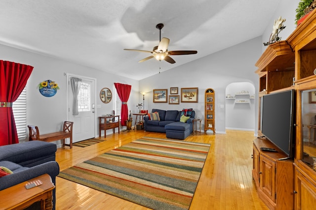 living room with light hardwood / wood-style flooring, ceiling fan, vaulted ceiling, and a textured ceiling