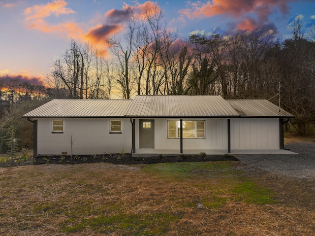 ranch-style home with metal roof and a lawn