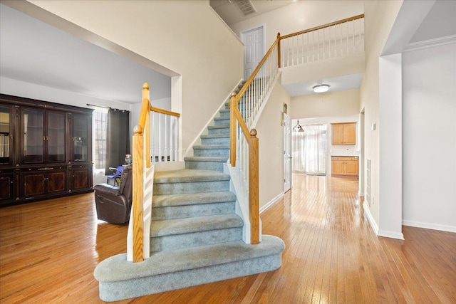 stairway featuring wood-type flooring and a towering ceiling