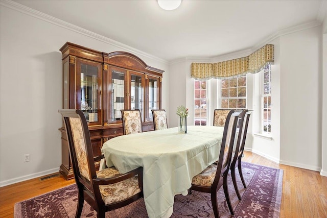 dining room with light hardwood / wood-style flooring and crown molding