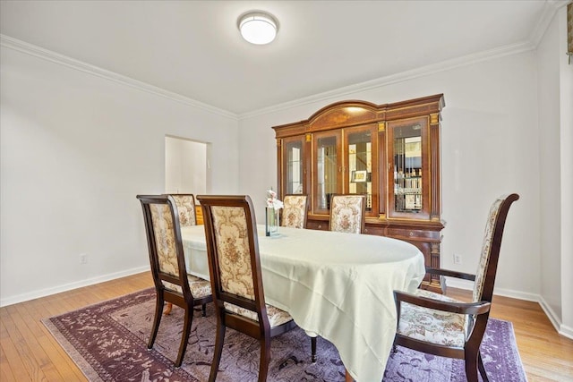 dining space featuring ornamental molding and light hardwood / wood-style flooring