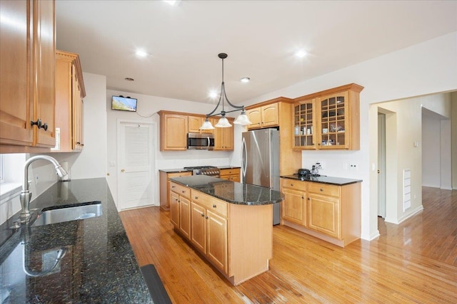 kitchen featuring sink, pendant lighting, light hardwood / wood-style floors, a kitchen island, and appliances with stainless steel finishes