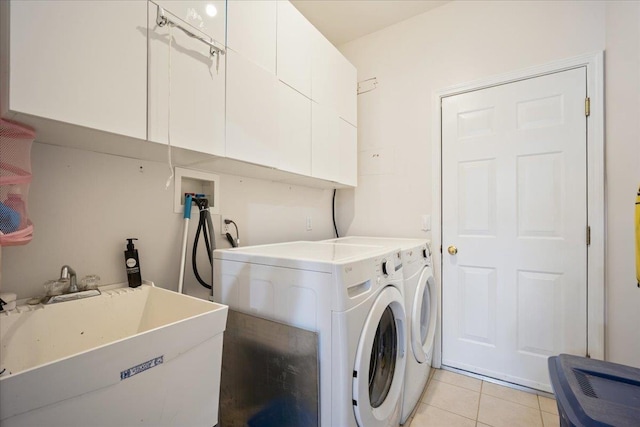 laundry room featuring sink, light tile patterned floors, cabinets, and independent washer and dryer