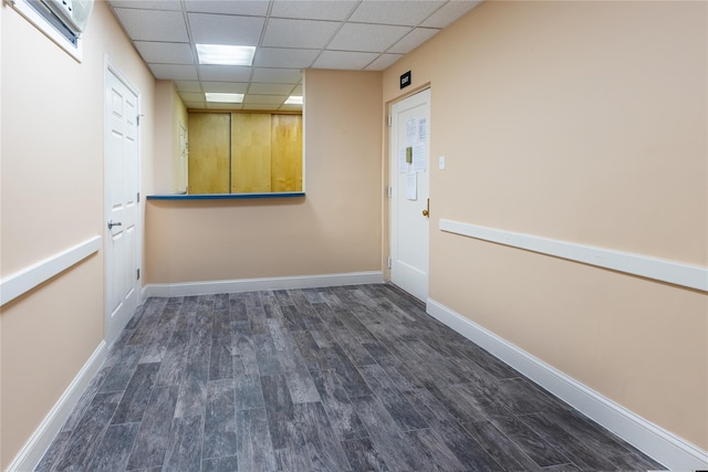 unfurnished room featuring a drop ceiling and dark wood-type flooring