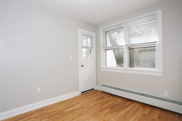 empty room with light hardwood / wood-style flooring and a baseboard heating unit